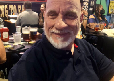 A elder man sitting in a bar smiling