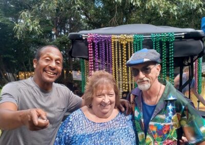 Three people posing for a photo in front of a Mardi Gras cart during a lively Blues Music event in Atlanta.