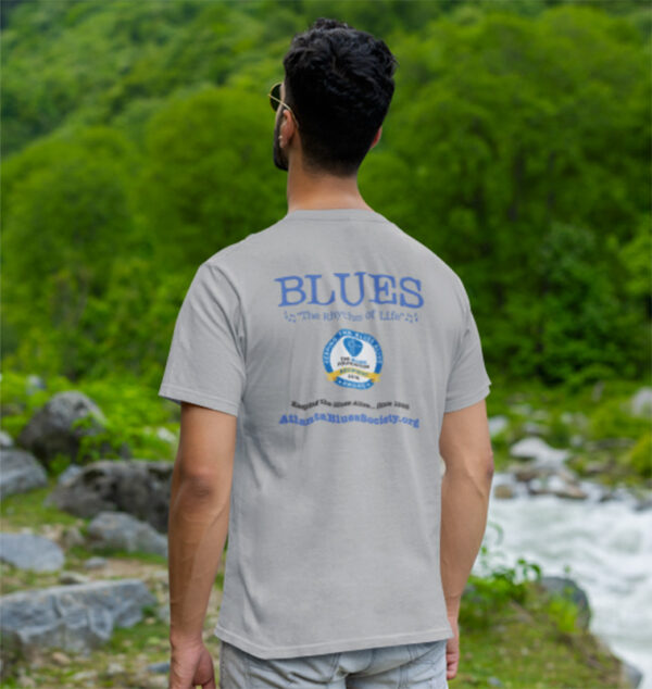 A man in a Georgia Blues T-shirt with text and graphics on the back standing outdoors with a view of a river and greenery.