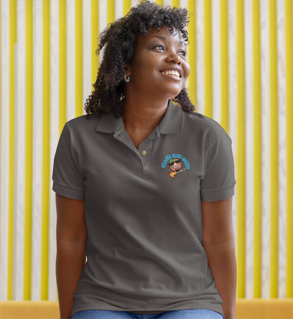 Woman wearing a dark polo shirt with a logo, smiling and looking upwards, with a yellow striped background.