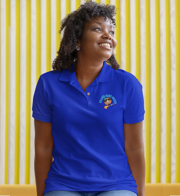 Woman smiling in blue polo shirt against yellow striped background.